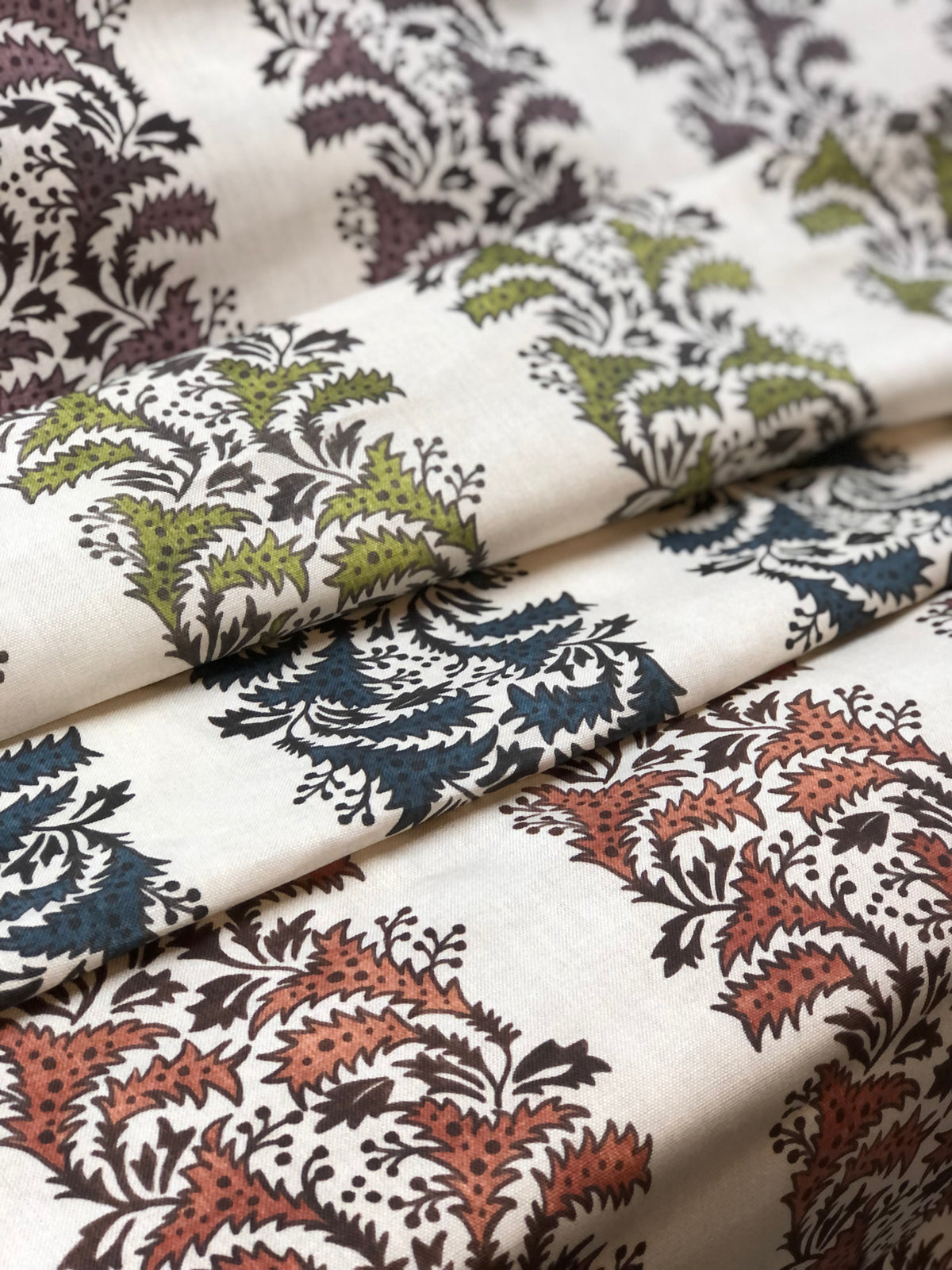 A collection of fabric amaya on Natural samples with floral and geometric patterns in various colors including blue, green, brown, and beige.