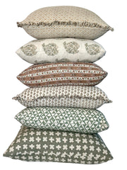 Stack of Bastideaux decorative pillows in layered green, brown and neutral patterned textiles