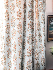 A San Marino drapery detail with a floral pattern in various colors, predominantly blue and green, with a ice blue linen background. next to gold framed art.