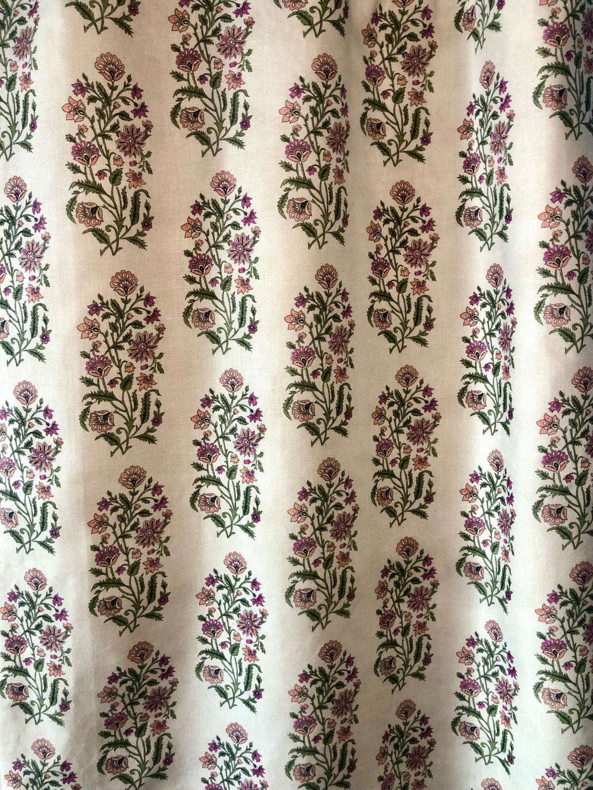 A close-up of a window drapery with a floral pattern in various colors including pink, orchid, and rose.