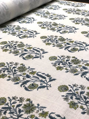 A San Marino textile print detail on a roll a floral pattern in various colors, predominantly blue and green, with a white linen background